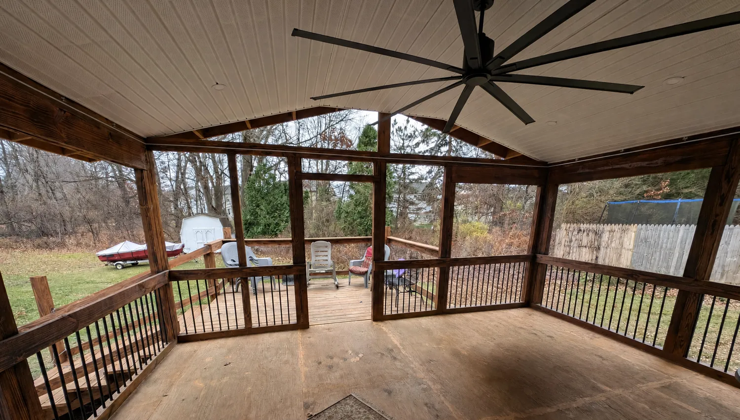 Finished covered porch with stained posts, black balusters, vaulted ceiling and ceiling fan